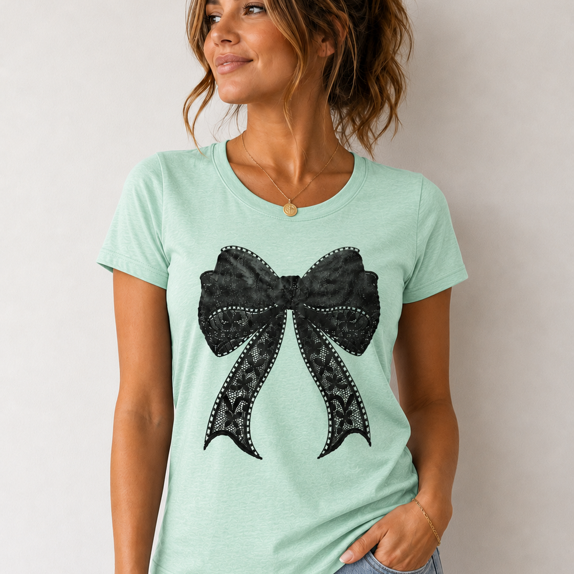 Woman wearing a light green t-shirt with a black bow design on a plain background