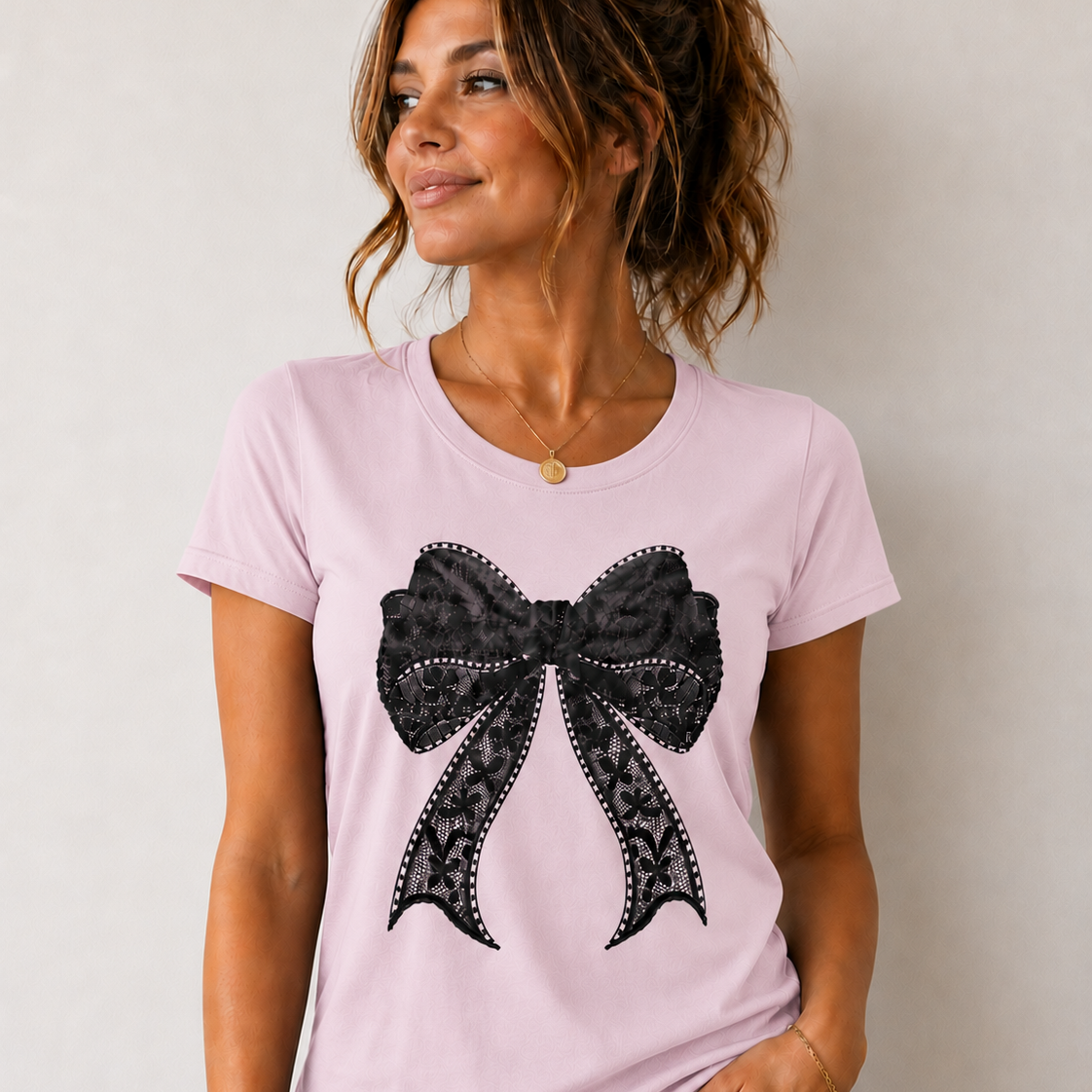 Woman wearing a pink t-shirt with a black bow design on a plain background
