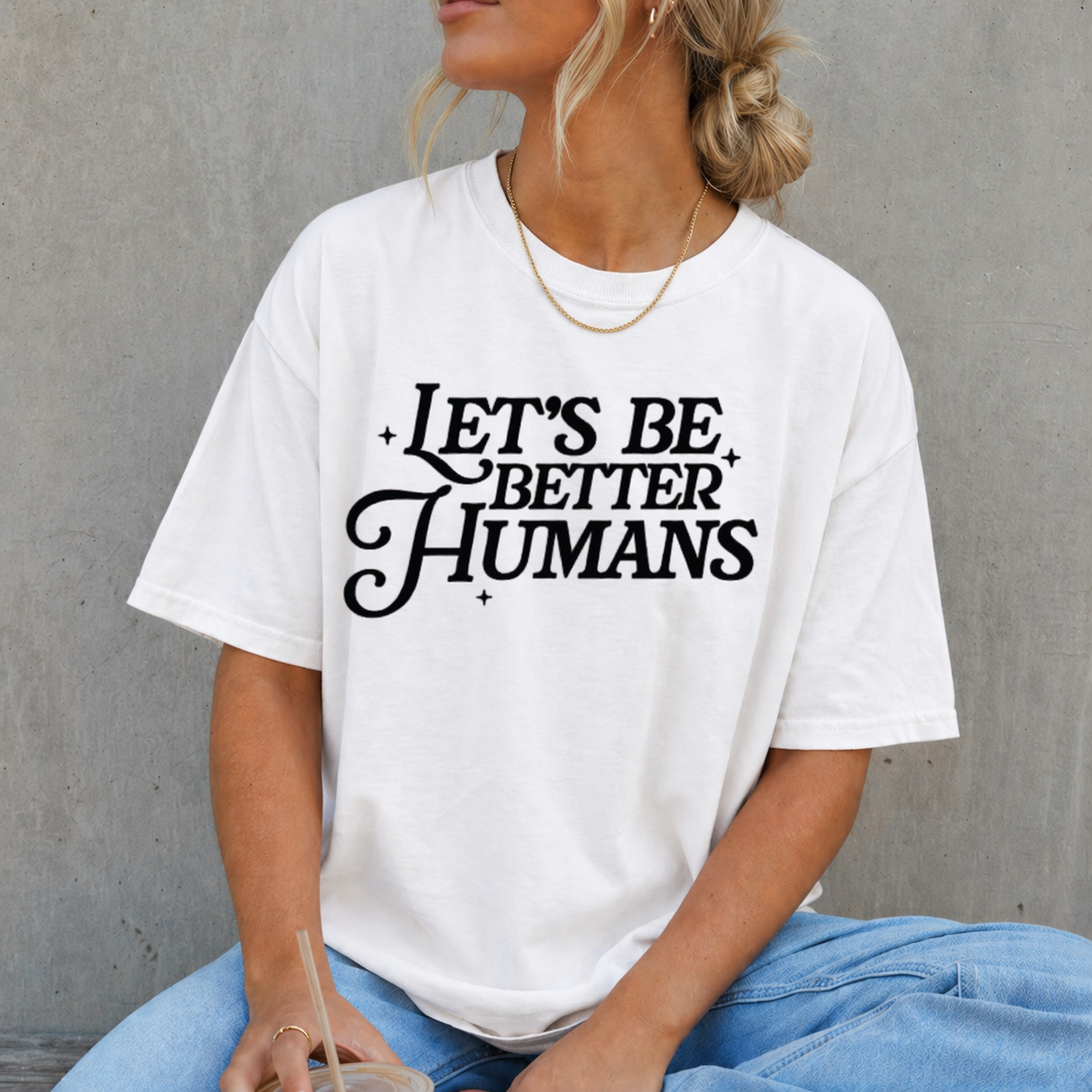 Person wearing a white t-shirt with 'Let's Be Better Humans' text against a gray background