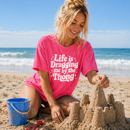 Woman in crunch berry colored t-shirt building a sandcastle on the beach