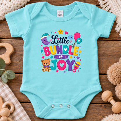 A caribbean blue short-sleeve baby bodysuit laid flat on a rustic wooden surface, featuring a colorful graphic that reads 'Little BUNDLE of JOY' with a teddy bear, balloons, stars, and hearts.