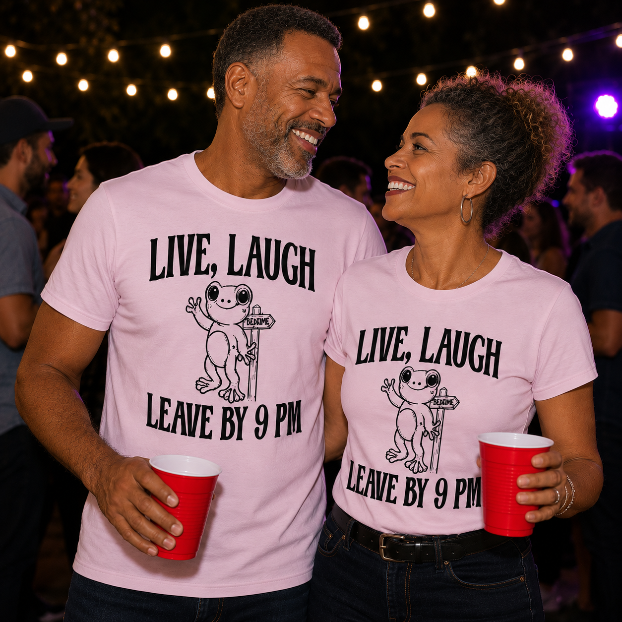 Two people wearing matching light pink colored t-shirts with a frog graphic and text "Live, Laugh Leave by 9pm holding red cups in a social setting.