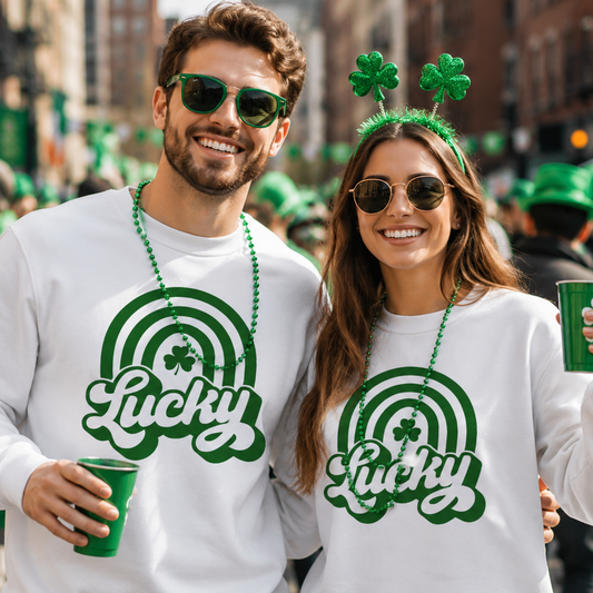 Two people wearing 'Lucky' white sweatshirts with shamrock designs at a St. Patrick's Day parade.