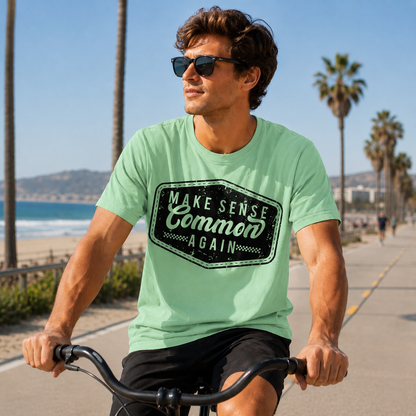 Man riding a bike wearing a mint green colored graphic  t-shirt that says Make Sense Common Again