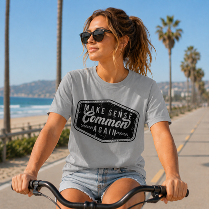 A Woman riding a bike wearing a sport grey colored graphic  t-shirt that says Make Sense Common Again