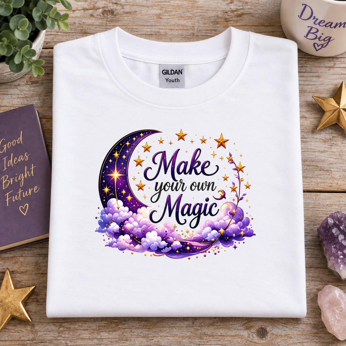 White t-shirt with moon, stars and clouds graphic with the Text Make your own Magic