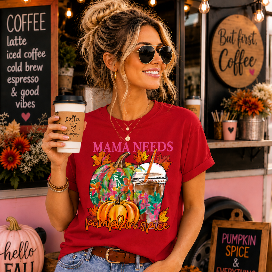 Woman wearing a red t-shirt with pumpkin spice design, holding a coffee cup in front of a coffee shop.