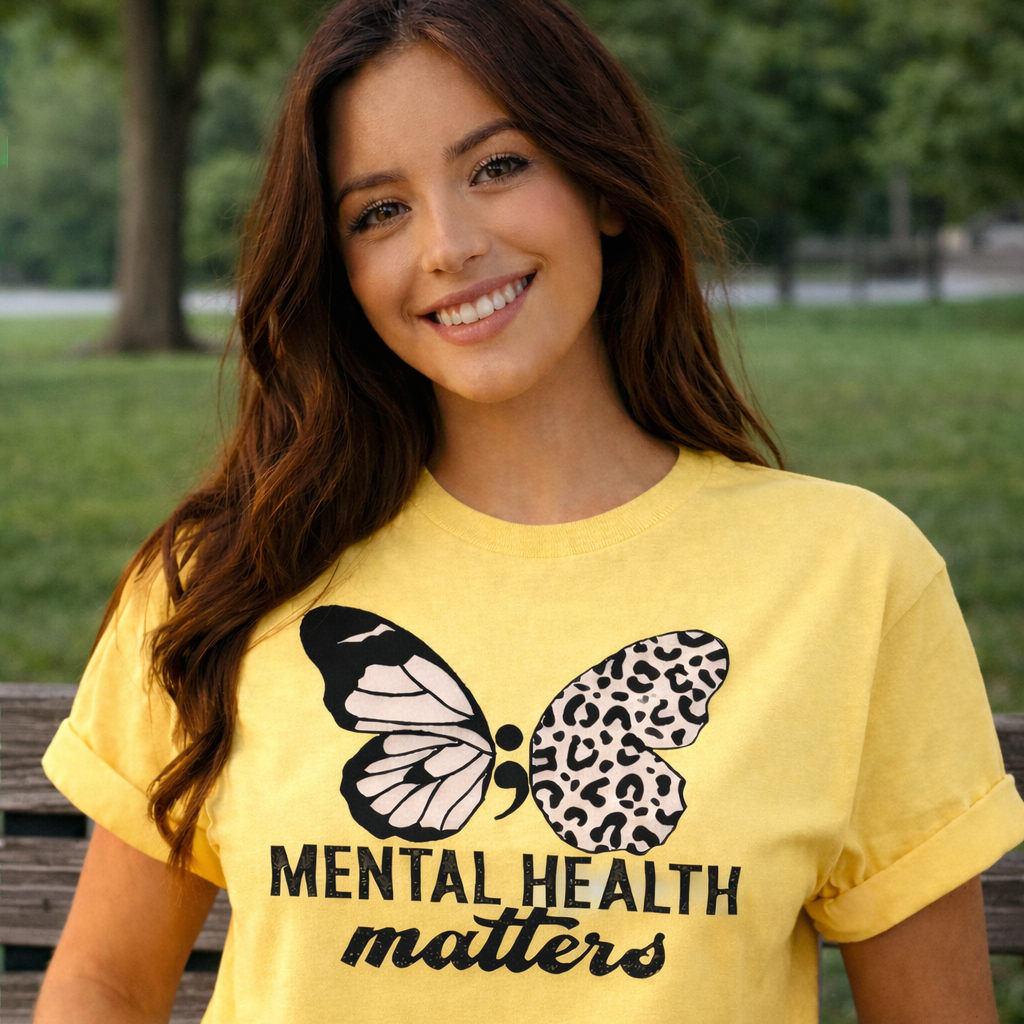 Woman wearing a yellow t-shirt with a butterfly graphic and 'Mental Health Matters' text in an outdoor setting.