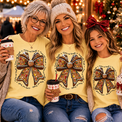 Three women posing together in matching yellow Christmas t-shirts featuring a large brown bow graphic with holiday text, set against a festive Christmas tree background.