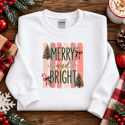 Merry and Bright Christmas graphic on a white sweatshirt with striped pink and coral background, white polka dots, green lettering, candy canes with red bows, and two decorated Christmas trees.