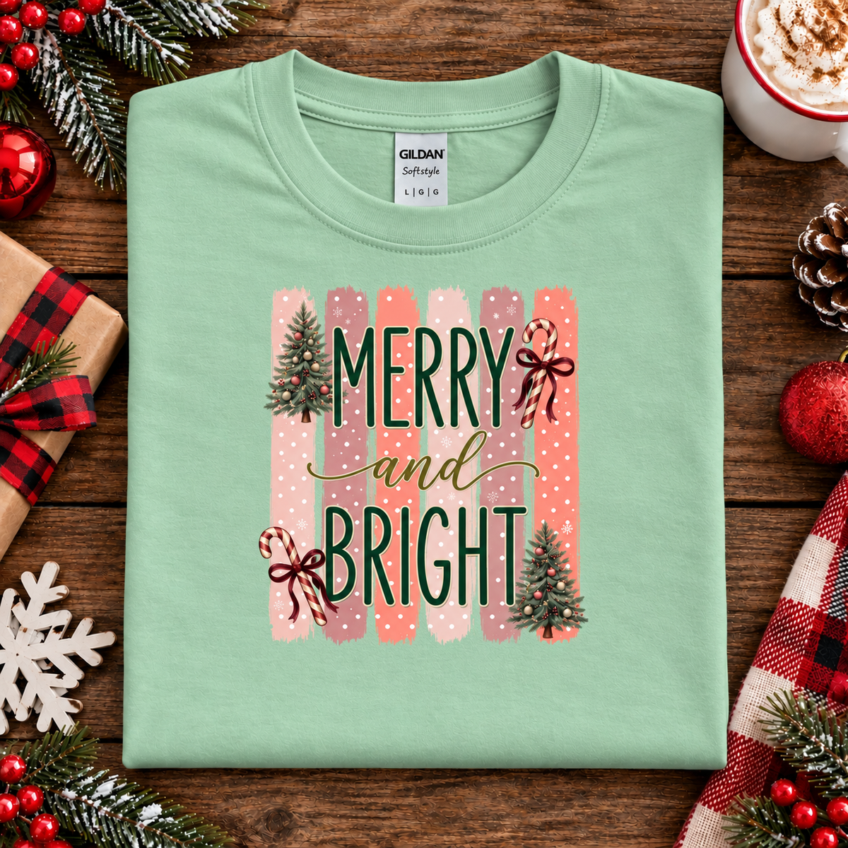 Merry and Bright Christmas graphic on a mint green t-shirt with striped pink and coral background, white polka dots, green lettering, candy canes with red bows, and two decorated Christmas trees.