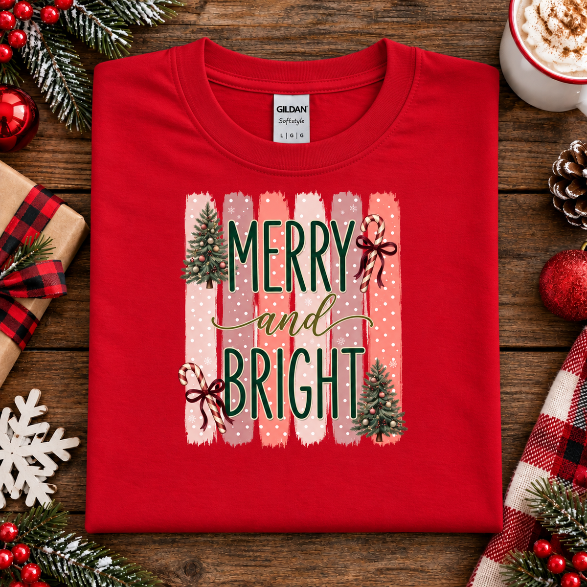 Merry and Bright Christmas graphic on a red t-shirt with striped pink and coral background, white polka dots, green lettering, candy canes with red bows, and two decorated Christmas trees.