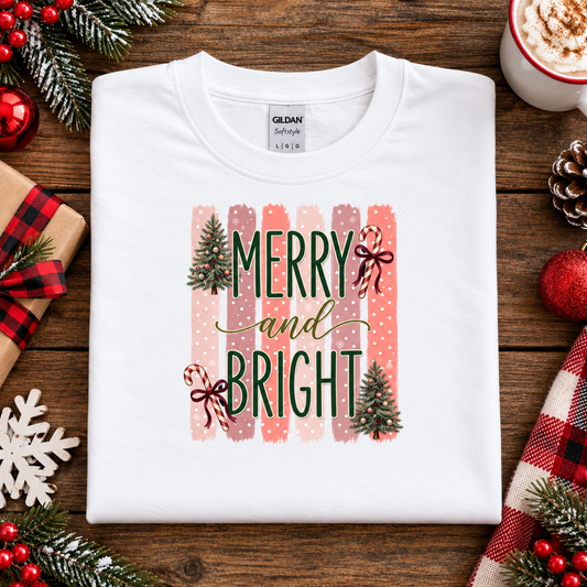 Merry and Bright Christmas graphic on a white t-shirt with striped pink and coral background, white polka dots, green lettering, candy canes with red bows, and two decorated Christmas trees.