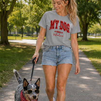 Woman walking a dog on a leash in a park wearing a sport grey colored  t-shirt with 'MY DOG IS MY VALENTINE' text.