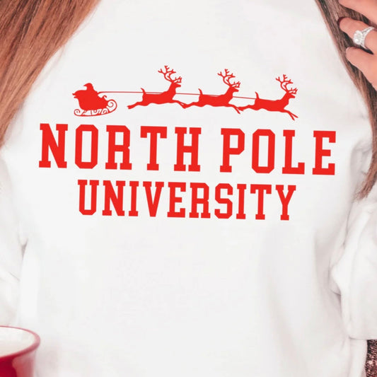 White sweatshirt with red 'North Pole University' text and Santa sleigh design.