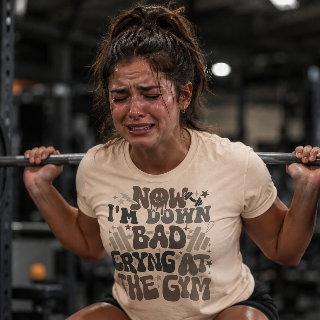 Woman lifting weights with a humorous natural colored t-shirt in a gym setting