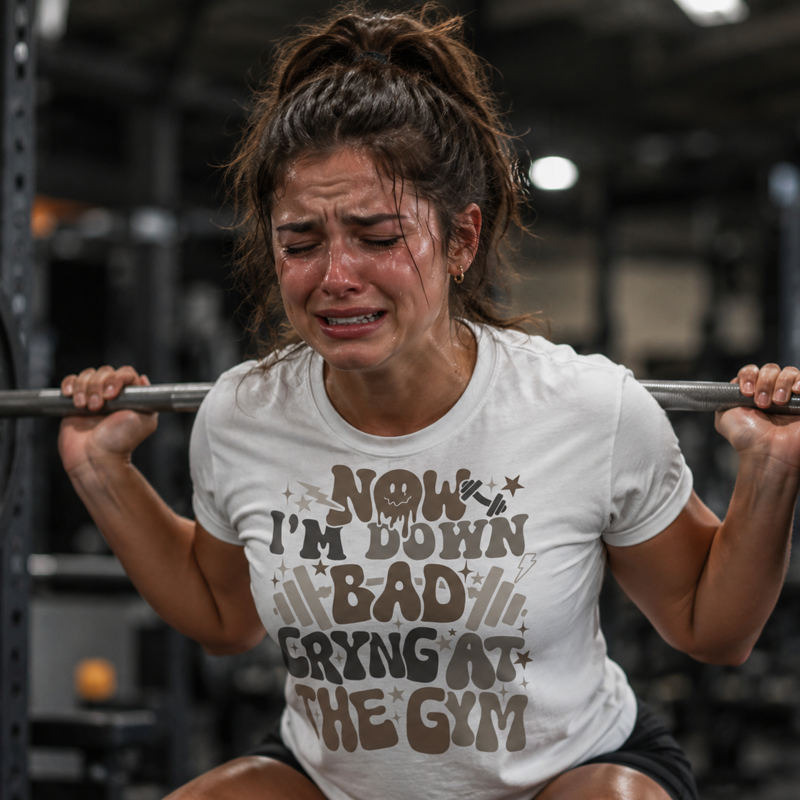 Woman lifting weights with a humorous white colored t-shirt in a gym setting