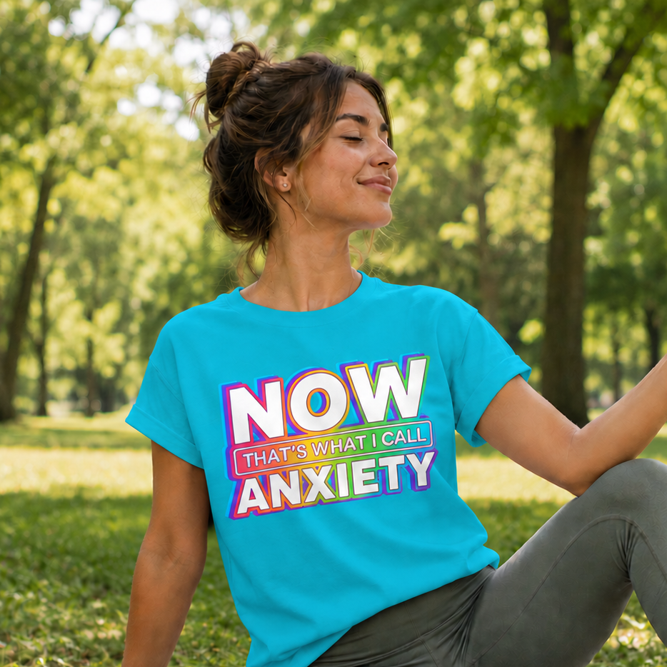 Person sitting on a yoga mat in a park wearing a blue t-shirt with colorful text.