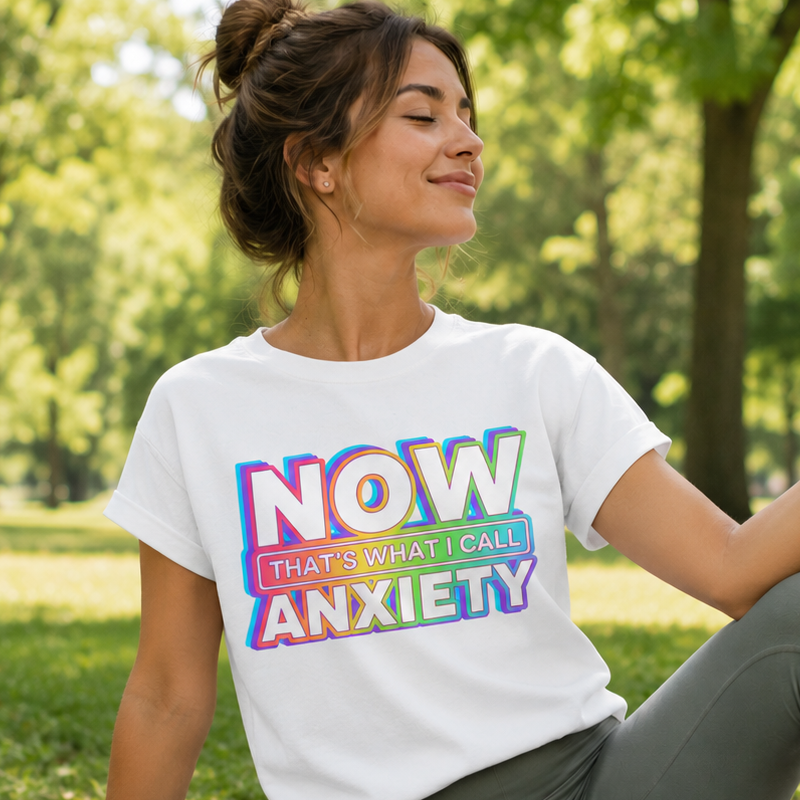 Woman sitting on a yoga mat in a park wearing a t-shirt with colorful text.