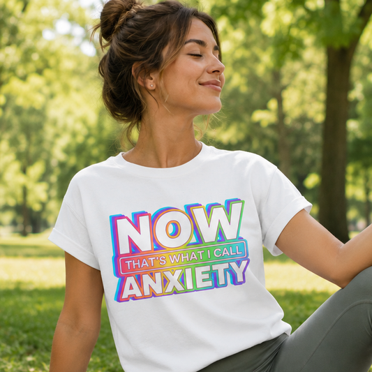 Woman sitting on a yoga mat in a park wearing a t-shirt with colorful text.