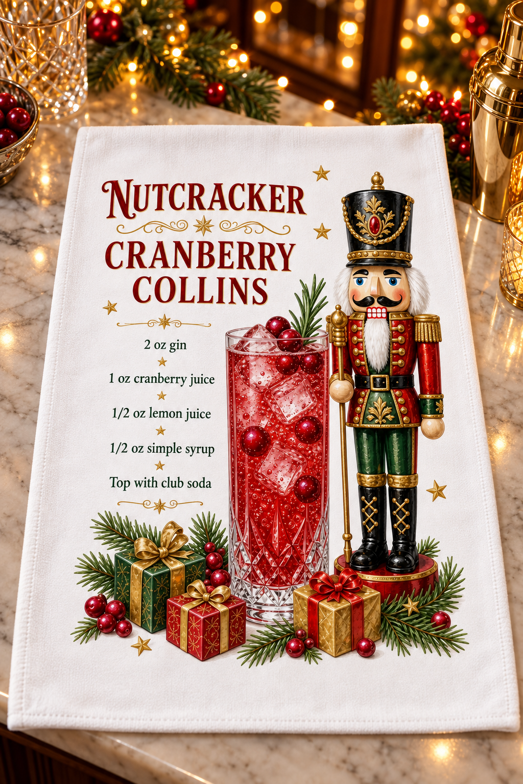 A white kitchen towel featuring a festive Christmas design with the text 'Nutcracker Cranberry Collins' and a recipe, decorated with an illustrated nutcracker, a red cranberry cocktail, gifts, and pine branches. 