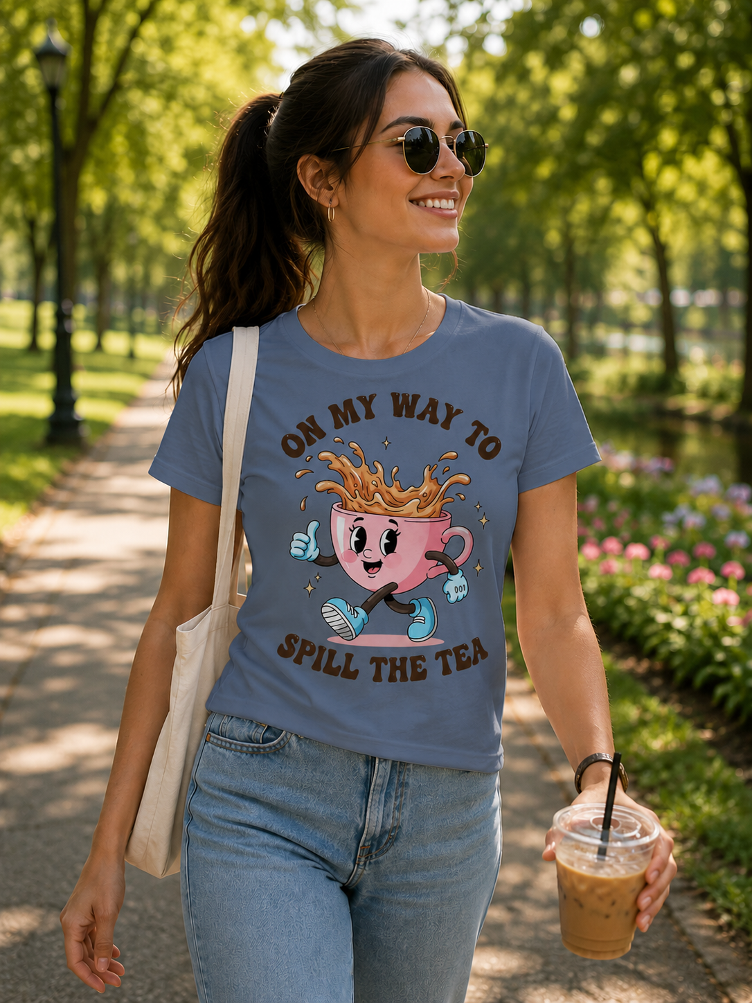 Blue Jean colored t-shirt with a graphic design cartoon pink cup character and text 'On my way to spill the tea' on a denim jacket background.
