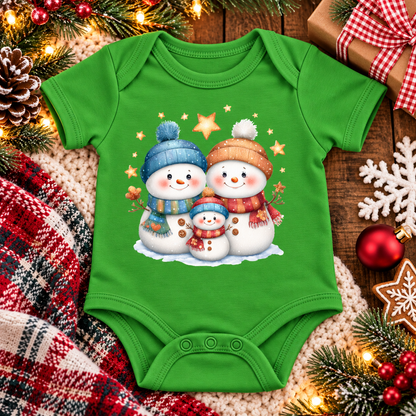 A apple green short-sleeve baby bodysuit with a festive Christmas graphic of three snowmen wearing blue and orange hats and scarves, surrounded by holiday decorations including pine branches, lights, a plaid blanket, and wrapped gifts.