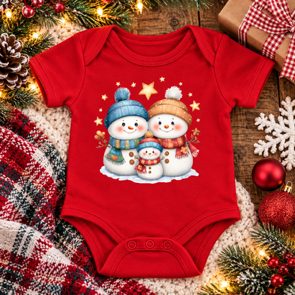 A red short-sleeve baby bodysuit with a festive Christmas graphic of three snowmen wearing blue and orange hats and scarves, surrounded by holiday decorations including pine branches, lights, a plaid blanket, and ornaments.