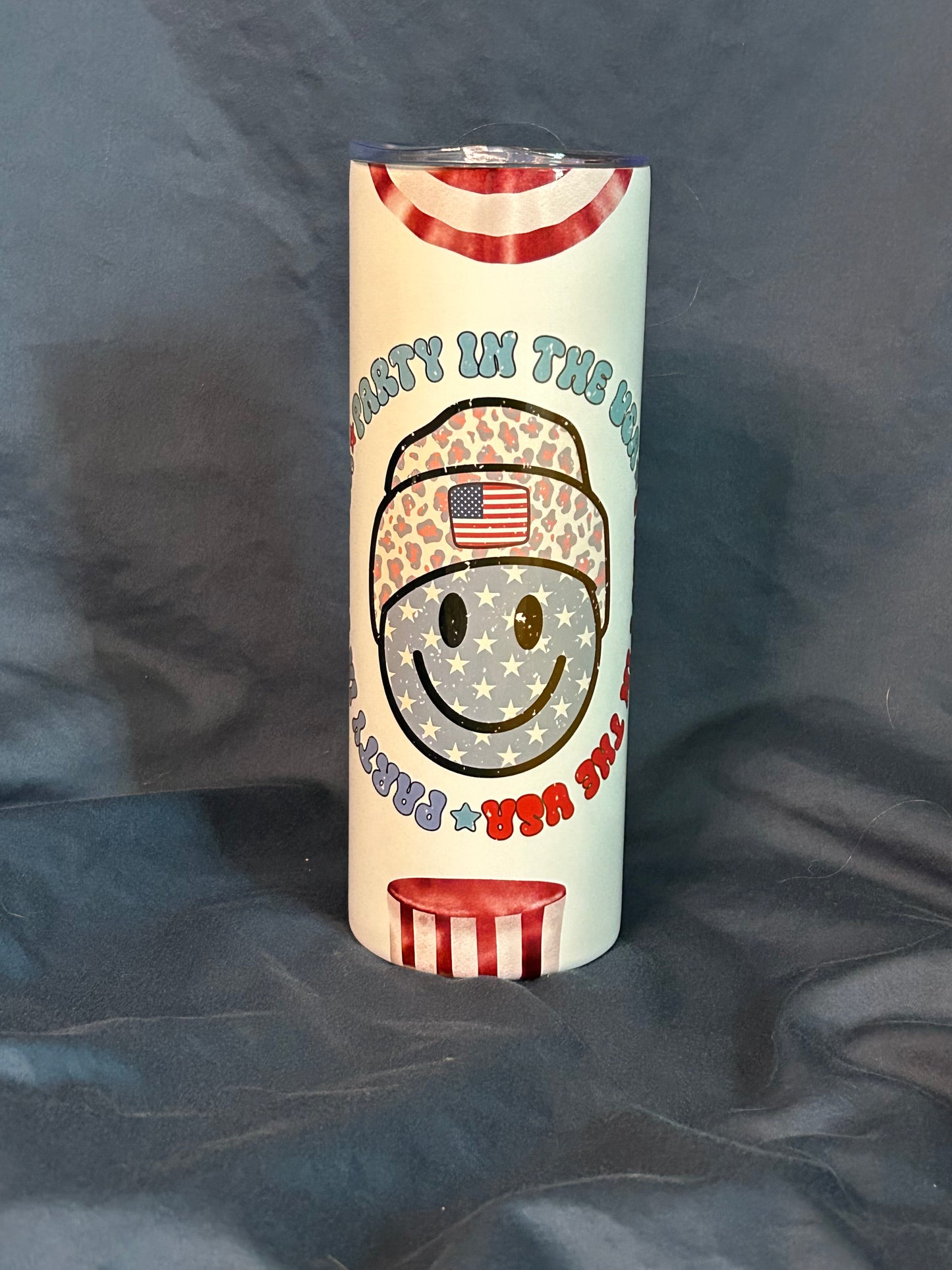 Tumbler with a design of a smiling face wearing a helmet with an American flag on a dark background