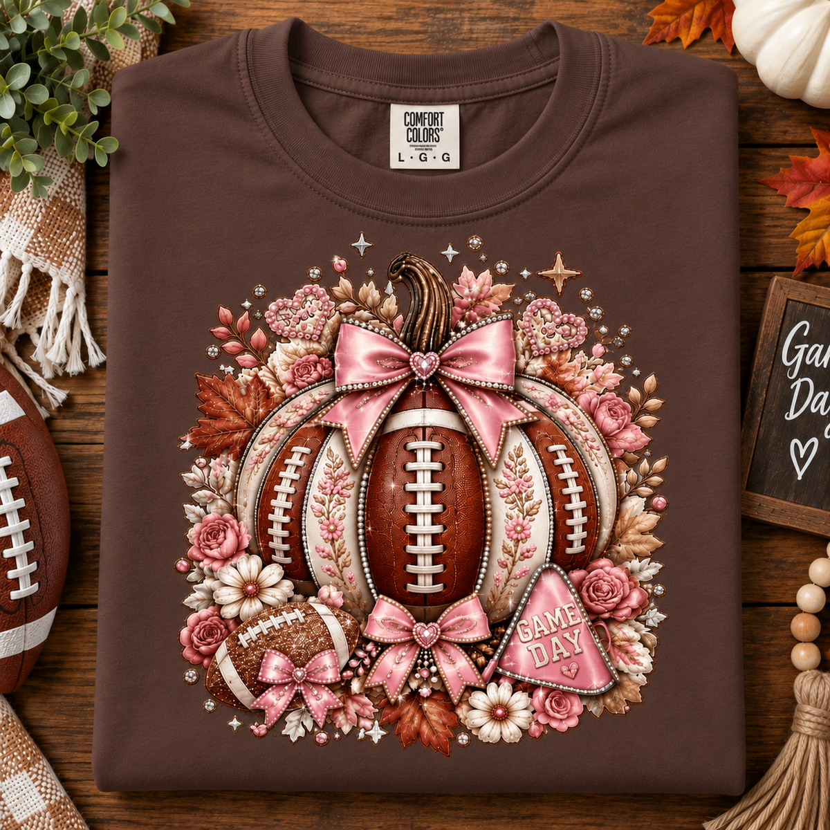 A folded expresso brown Comfort Colors t-shirt with a detailed autumn football graphic, displayed on a rustic wooden background with seasonal props.
