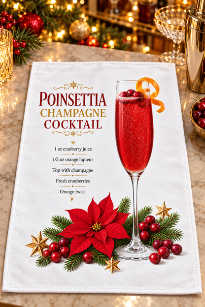 A white kitchen towel featuring a festive 'Poinsettia Champagne Cocktail' design, laid flat on a table with holiday lights and garnishes in the background.