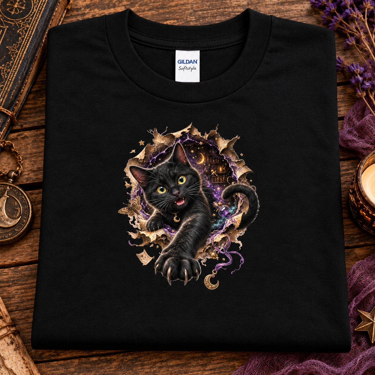 A black graphic T-shirt featuring a 3D black cat with glowing golden-green eyes reaching through a torn magical portal, surrounded by purple mystical energy, crescent moons, stars, and witchy details