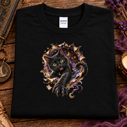 A black graphic T-shirt featuring a 3D black cat with glowing golden-green eyes reaching through a torn magical portal, surrounded by purple mystical energy, crescent moons, stars, and witchy details