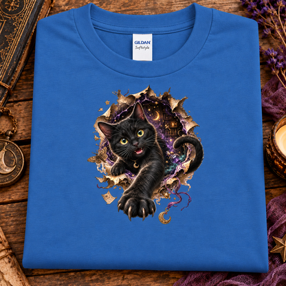 An iris colored graphic T-shirt featuring a 3D black cat with glowing golden-green eyes reaching through a torn magical portal, surrounded by purple mystical energy, crescent moons, stars, and witchy details