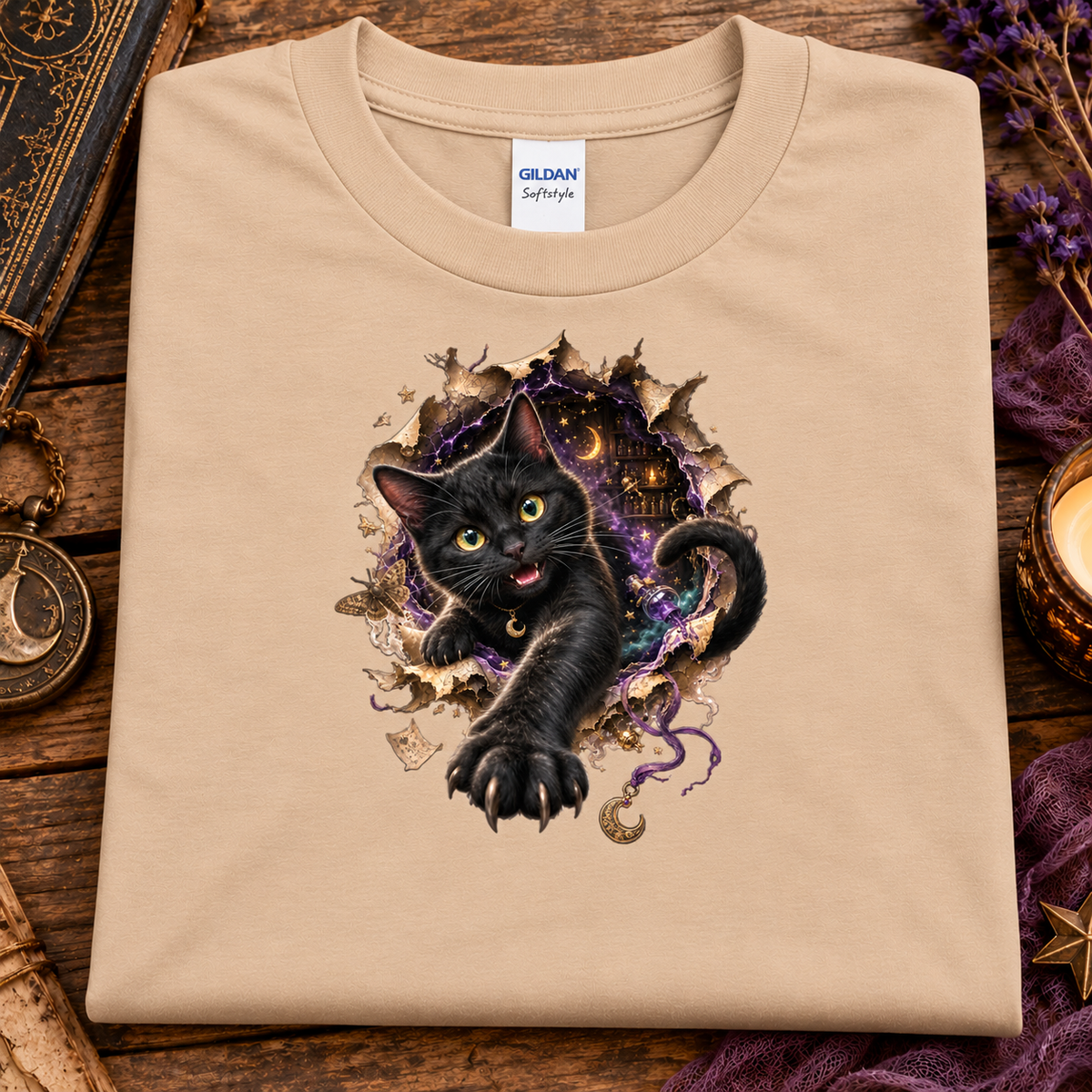 A natural colored graphic T-shirt featuring a 3D black cat with glowing golden-green eyes reaching through a torn magical portal, surrounded by purple mystical energy, crescent moons, stars, and witchy details