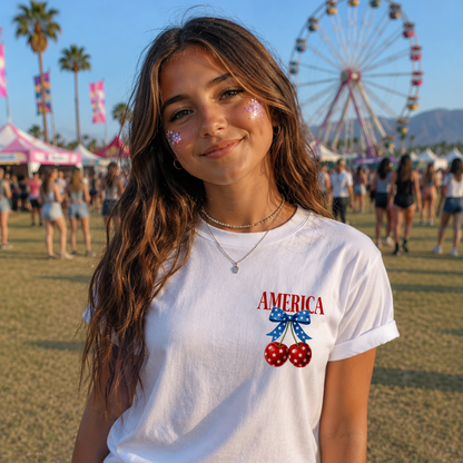 Girl wearing a white t-shirt with America text with red, white and blue cherry graphic design on pocket