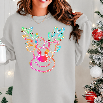 Person wearing a ash gray sweatshirt with a colorful neon reindeer design, standing in front of a decorated Christmas tree.