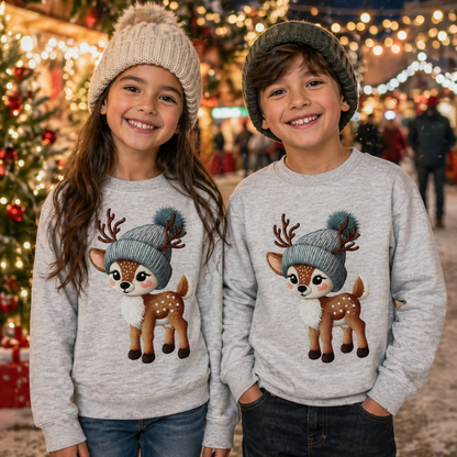 Two children wearing matching sport gray sweatshirts with a deer design in front of a Christmas tree.
