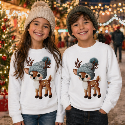 Two children wearing matching white sweat shirts with deer illustrations in a festive outdoor setting.