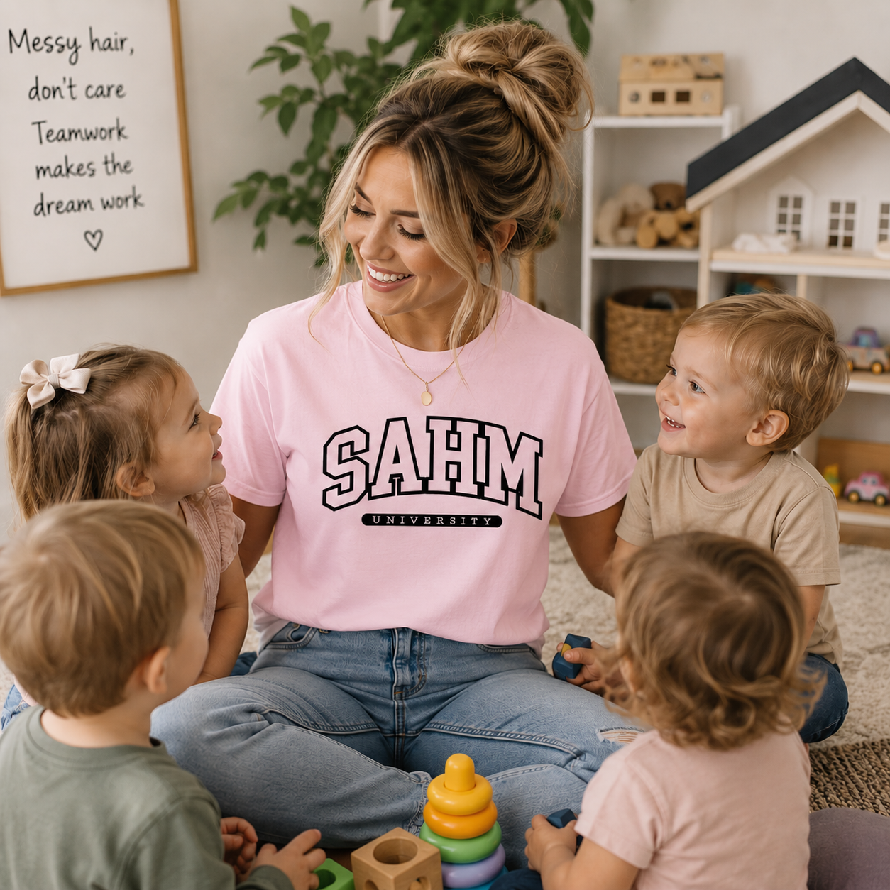 Woman in a pink 'SAHM University' shirt sitting with four children in a home setting.