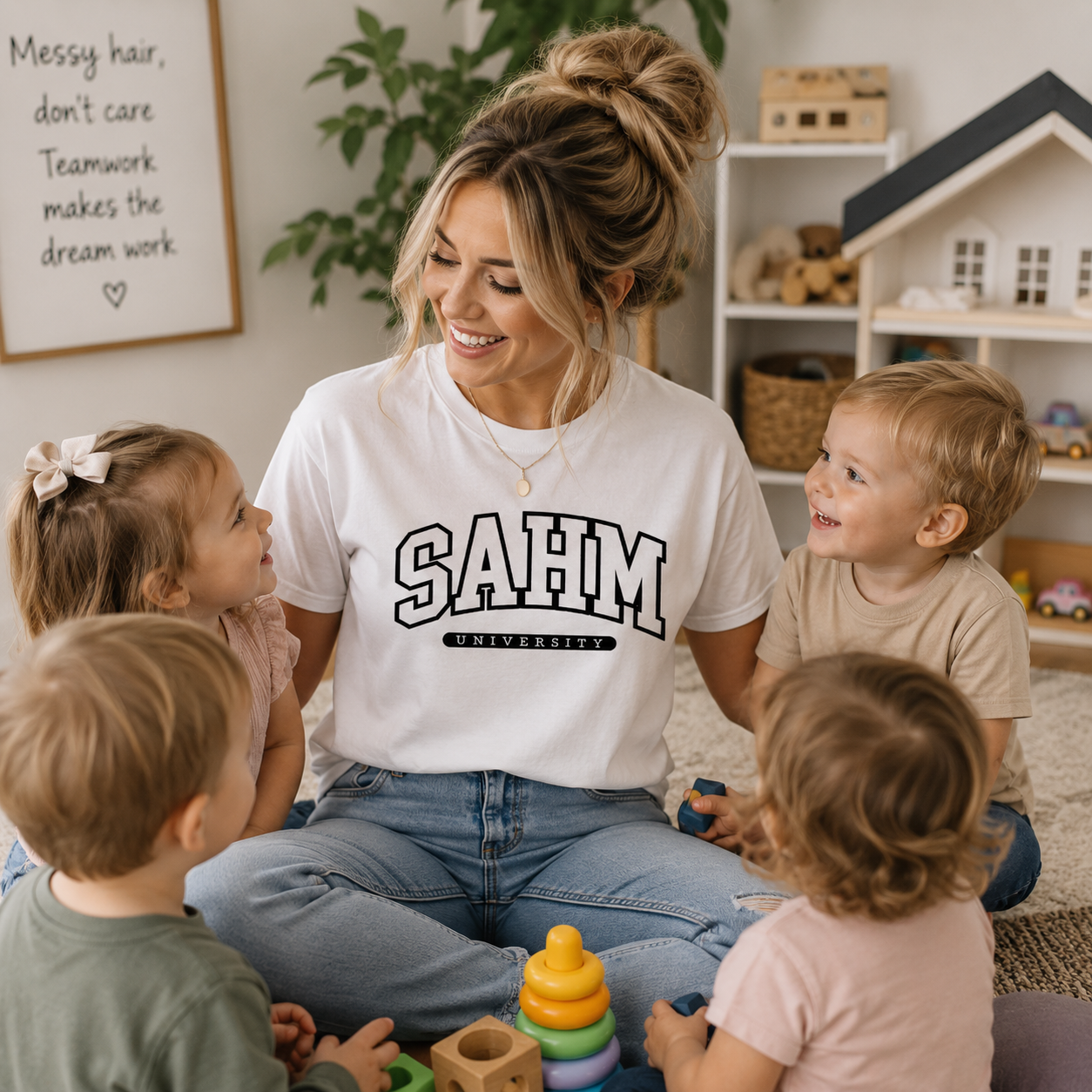 Woman in a 'SAHM University' shirt sitting with four children in a home setting.