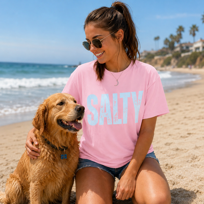 Woman in pink 'SALTY' t-shirt with dog on beach