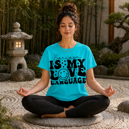 Woman meditating outdoors wearing a blue t-shirt with 'Sarcasm is my love language' text.