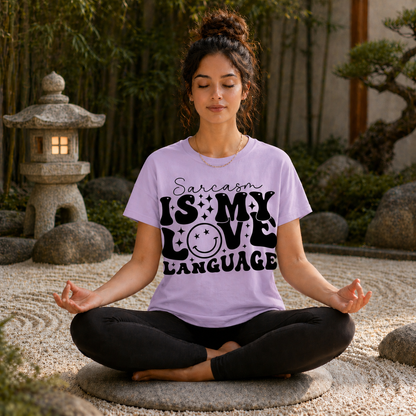 Woman meditating outdoors wearing an orchid colored t-shirt with a humorous text "Sarcasm is my love  language" design.