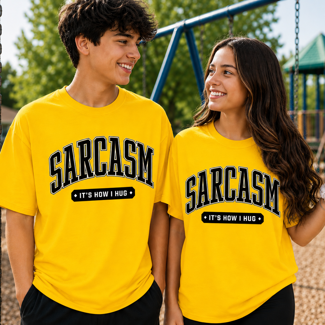 Two people wearing yellow t-shirts with 'SARCASM IT'S HOW I HUG' text on a playground.