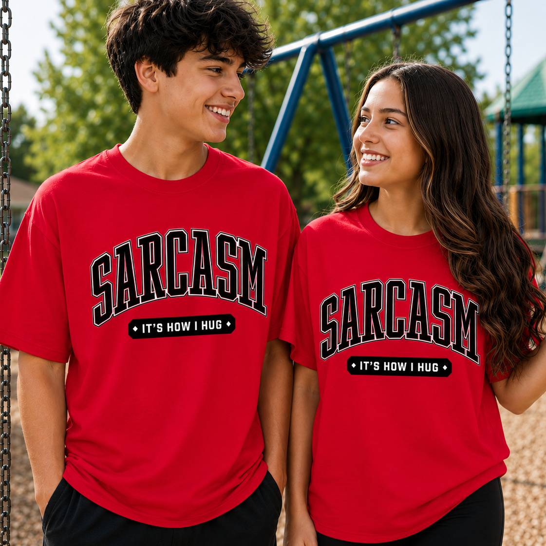 Two people wearing red t-shirts with 'SARCASM IT'S HOW I HUG' text on a playground.