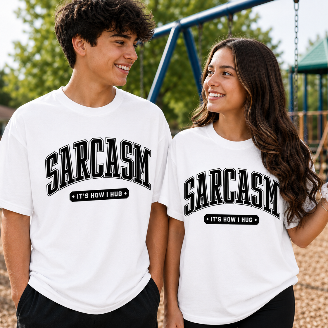 Two people wearing white t-shirts with 'SARCASM IT'S HOW I HUG' text on a playground background.