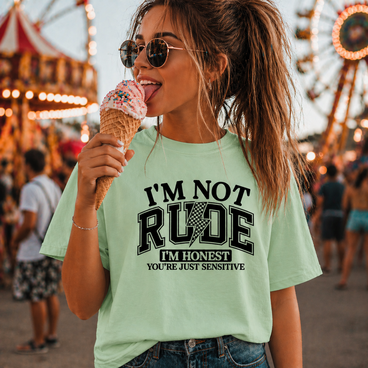 Woman eating ice cream at a fair wearing a mint green colored t-shirt with humorous text.