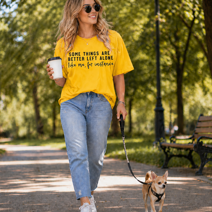Woman walking a dog in a park wearing a yellow graphic t-shirt with text.