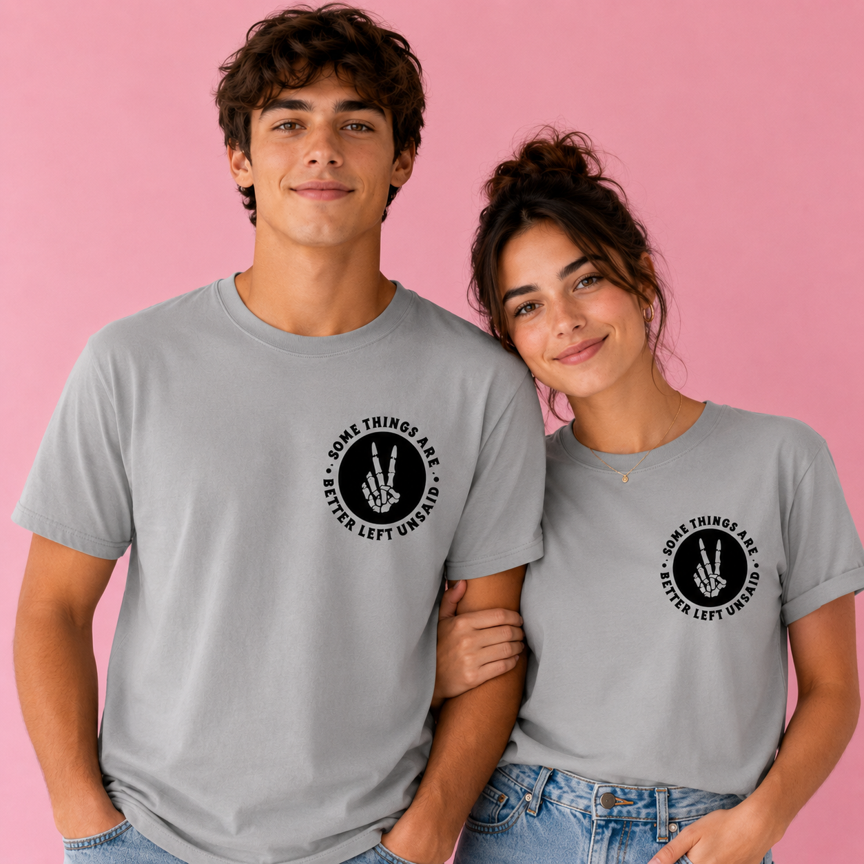 Two people wearing gray t-shirts with a black graphic design on a pink background
